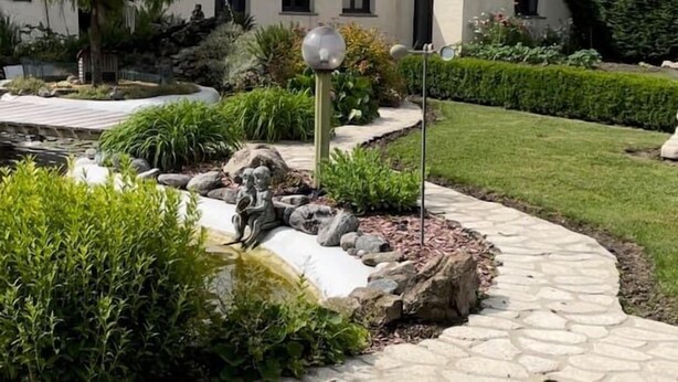 Un bâtiment moderne avec un chemin de pierre menant à un bassin orné d’une statue.