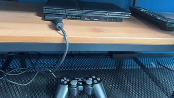 Ein Laptop auf einem Holztisch mit Tastatur, Maus und zwei Spielecontrollern.