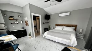 Un dormitorio moderno con una cama grande, mesitas de noche, un escritorio y una silla.