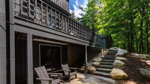 A modern outdoor seating area with Adirondack chairs and a stone staircase leading up to a wooden deck. - Hupi House: A Peaceful, Wooded, Lakeside Sanctuary (Monterey)