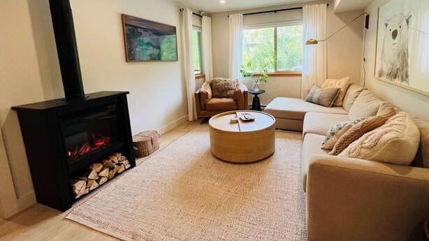 Una sala de estar acogedora con chimenea, una mesa redonda para café, un sofá y un cuadro en la pared.
