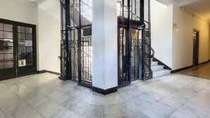 A spacious hallway with a black metal gate and a staircase leading to an upper level.