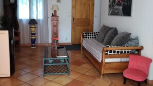 Una sala de estar con un sofá, una mesa de centro, una silla roja, un reloj, una lámpara y una puerta.