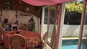 Un patio cubierto con mesa y sillas, una piscina y vistas al exterior.