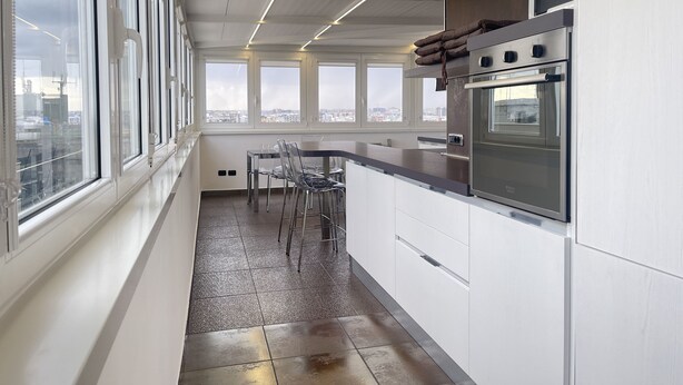 A modern kitchen with large windows, a stainless steel oven, and a dining area with chairs. - SkyLine (Bari)