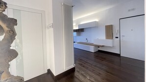 A modern interior with a wooden floor, white walls, and a built-in kitchen area with a countertop and sink. - SkyLine (Bari)