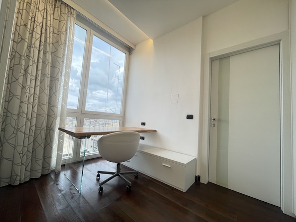 Ein Zimmer mit Schreibtisch, Stuhl und einer Tür.