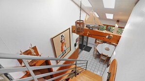 Un intérieur moderne avec un escalier en bois, un coin repas et une lanterne suspendue.