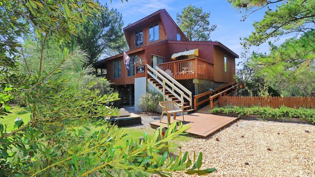 Une cabane en bois à deux étages, dotée d’une terrasse et d’un escalier menant à l’étage supérieur.