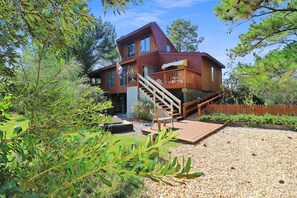 A two-story wooden cabin with a deck and stairs leading to the upper level. - Admiral Benbow | Oyster Bay Home Next to Boat Ramp & Dock w/ Screened Porch (Chincoteague Island)