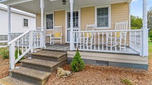 A house with a porch, steps, and a small tree.