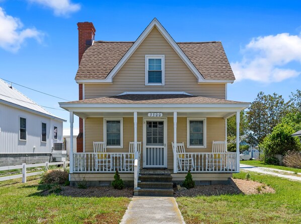 A two-story house with a front porch, a chimney, and a number '3300' on the door. - Almost Heaven | Waterfront w/ Private Pier & Boat Dock, Pet Friendly, Fireplace, Sunset Views (Chincoteague Island)