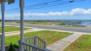 A coastal road with a pier extending into the water, a clear sky, and a white building with a sign.