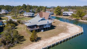 Une propriété située au bord de l’eau, avec une grande maison dotée d’une terrasse couverte et de plusieurs niveaux.