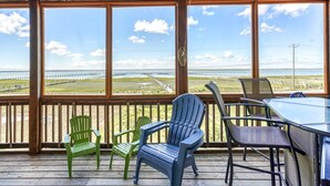 Un espace extérieur abrité, aménagé avec des sièges, et offrant une vue sur une plage et une clôture.