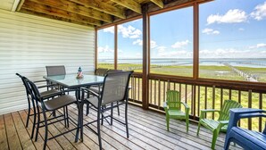 Un espace extérieur abrité, doté d’une table et de chaises, offrant une vue sur l’eau et comprenant une terrasse en bois.