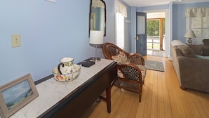 Una habitación con una mesa de comedor, sillas, un sofá, una lámpara y un espejo.