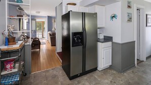 Una cocina moderna con un refrigerador grande, piso de madera y armarios blancos.
