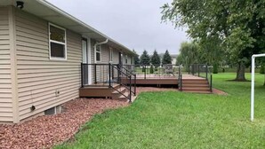 A single-story house with a front porch, a small deck, and a well-maintained lawn.