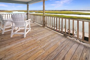 A wooden deck with Adirondack chairs overlooking a marshy landscape with water and greenery. - Dockside | Assateague Channel Home w/ Pony Views, Private Dock for Boats, Decks & Wood Fireplace (Chincoteague Island)