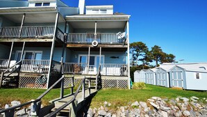 Un bâtiment à deux étages doté d’un balcon, d’un porche et d’un petit espace extérieur avec des marches menant à l’entrée.