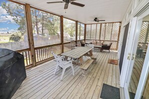A covered patio with a wooden table and chairs, a ceiling fan, and a view of the backyard. - Herbie's Hideaway | Luxury Water Views, Dock Access & Screened Porch Near Memorial Park (Chincoteague Island)