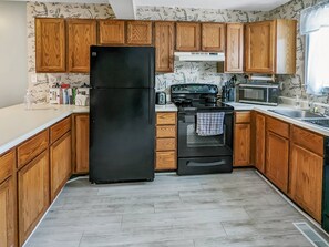 Fully equipped kitchen with a refrigerator, stove, microwave, and sink.
