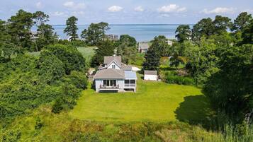 A house with a large lawn and a view of the sea.