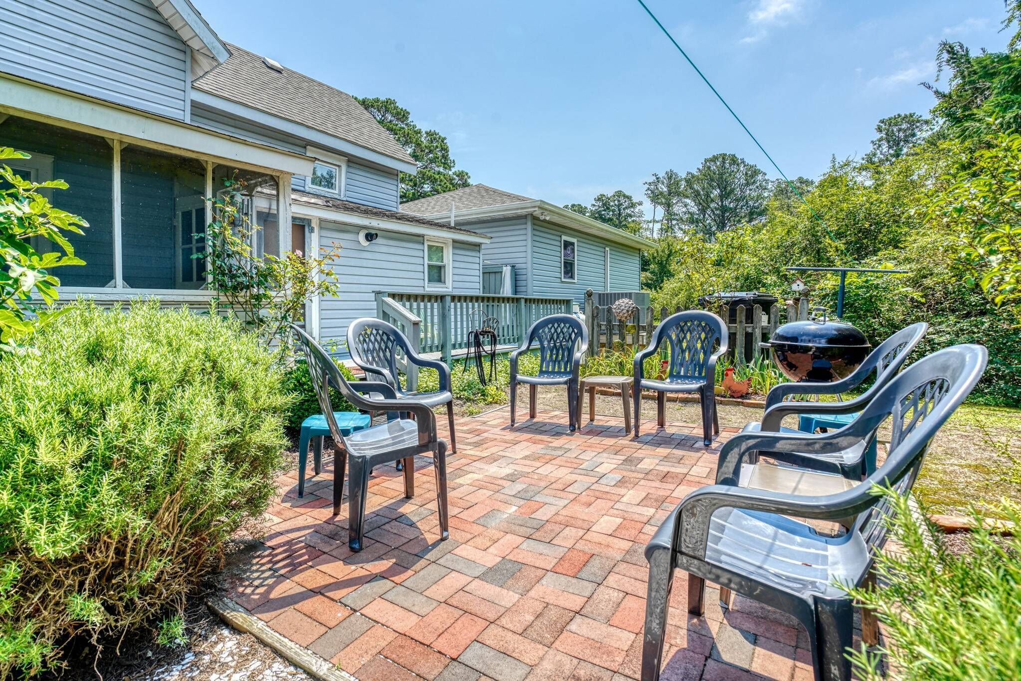A patio area with plastic chairs and a barbecue grill.