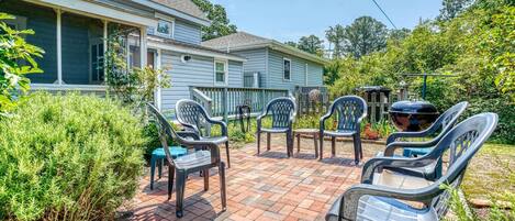 A patio area with plastic chairs and a barbecue grill.