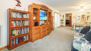Una sala de estar acogedora con un mueble de centro de entretenimiento de madera, una estantería y un sofá cómodo.