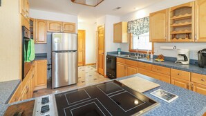 Una cocina moderna con gabinetes de madera, un refrigerador de acero inoxidable, un lavavajillas, una estufa y una cafetera.