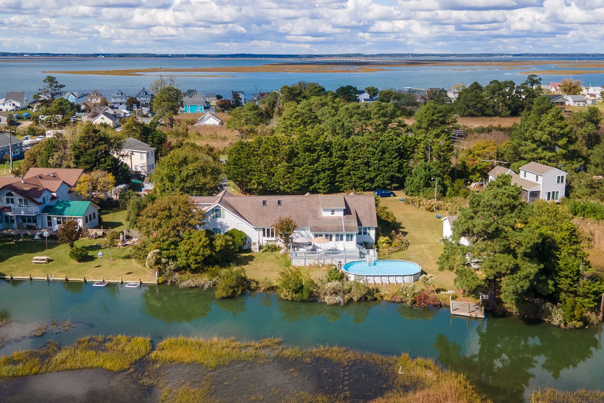 A residential area with houses, a swimming pool, and a body of water.