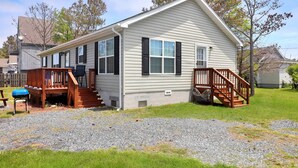 A single-story house with a front deck, a covered porch, and a small staircase leading to the front door. - My Island Escape | Luxury New Home, Gourmet Kitchen, Soaking Tub, Deck Retreat Near North Main (Chincoteague Island)