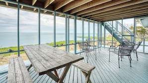 A wooden deck with a table and chairs overlooking a body of water. - Poole's Cove | Waterfront Main Street Retreat Fully Renovated w/ Rooftop Lounge & Artistic Charm (Chincoteague Island)
