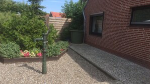 A courtyard with a gravel path, a wooden fence, and a brick building.