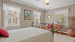 A bedroom with a bed, a desk, and a chair. - Serendipity | Classic Chincoteague Home Walk to Main Street w/ Screened Porch & First-Floor Bedroom (Chincoteague Island)