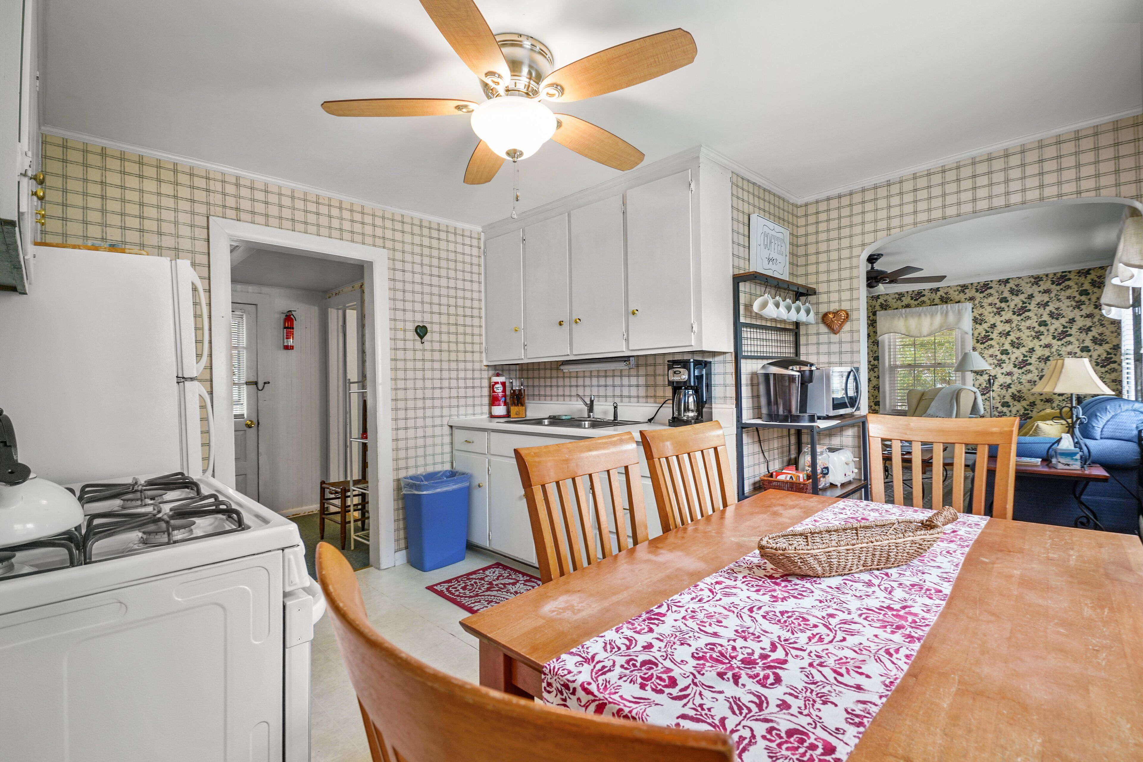 A compact kitchen with white cabinets, a gas stove, and a ceiling fan.
