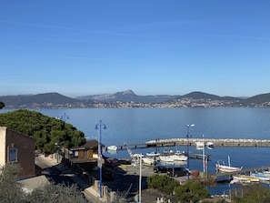 A marina with boats docked, a clear sky, and a mountainous backdrop.