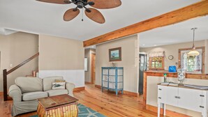 A spacious living room with a wooden floor, a beige sofa, a wooden coffee table, and a blue cabinet. - Shady Side | Piney Island Home Near Beach w/ Community Water Access, Large Porch, Grill & Loft (Chincoteague Island)