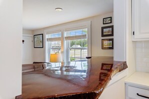 A kitchen with a marble countertop, a window with blinds, and framed artwork on the wall.