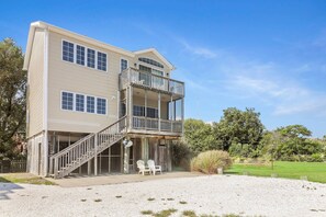 A two-story house with a balcony, a covered porch, and a gravel driveway.
