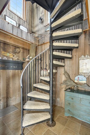 Un escalier en colimaçon avec des marches en bois et un arbre à chat fixé au mur.
