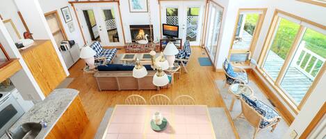 Amplia sala de estar con chimenea, televisor y una mesa de comedor con sillas.