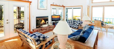 Un salón amplio con chimenea, asientos cómodos y grandes ventanales con vistas al exterior.