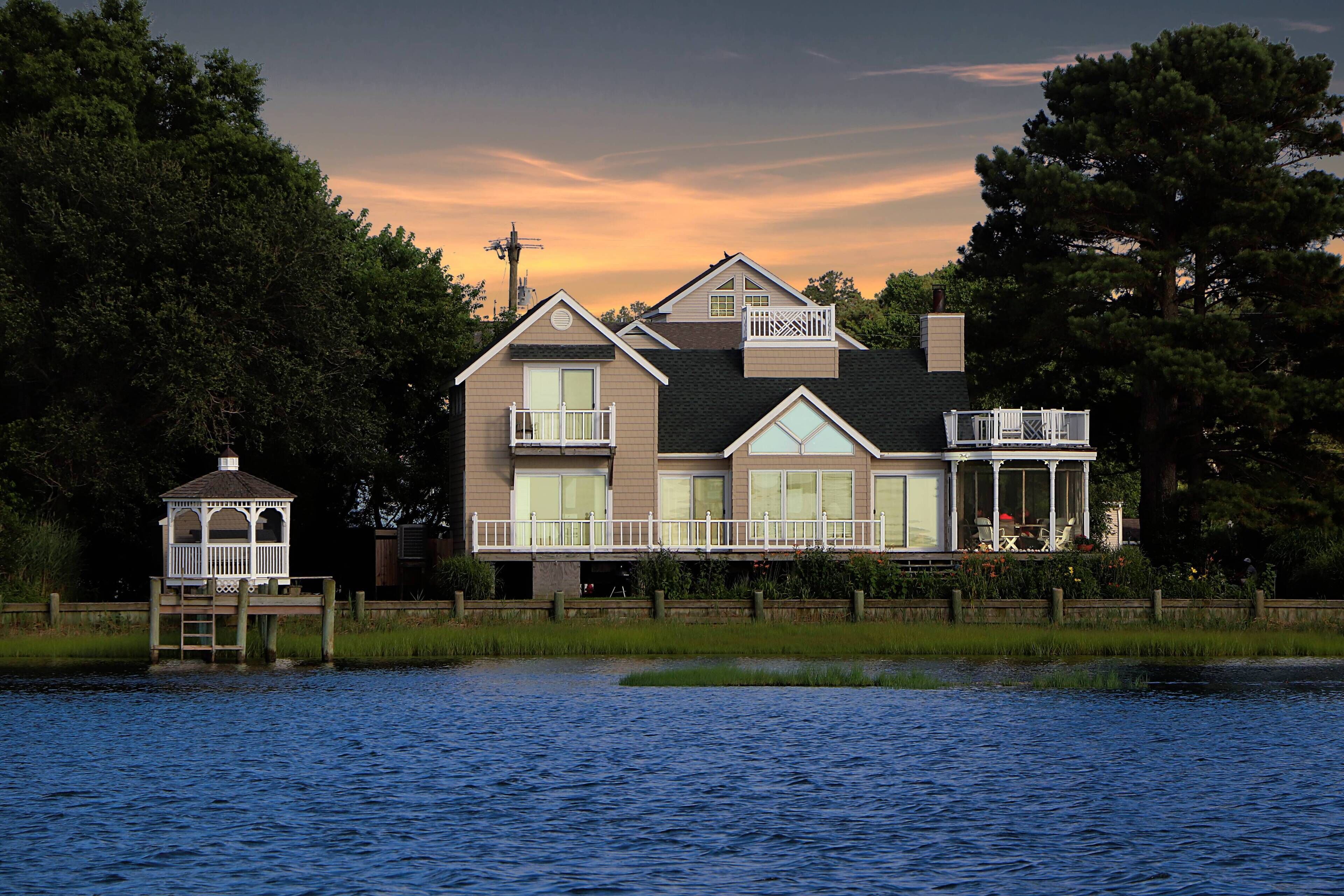 A two-story house with a balcony and a dock extending into a body of water.