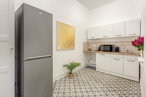 A modern kitchen with white cabinets, a grey refrigerator, a microwave, and a coffee maker. - Family Suite - Marais - Martin III (Paris)