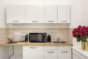 A modern kitchen with white cabinets, a microwave, a toaster, and a sink.