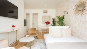 Een moderne hotelkamer met een bed, een zithoek met een stoel en een tafeltje, een aan de muur bevestigde televisie en een decoratief wandpaneel.