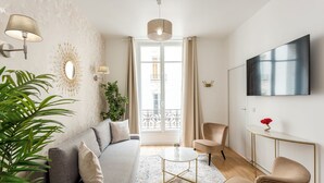 Een moderne woonkamer met een bank, stoelen, een salontafel en een televisie.